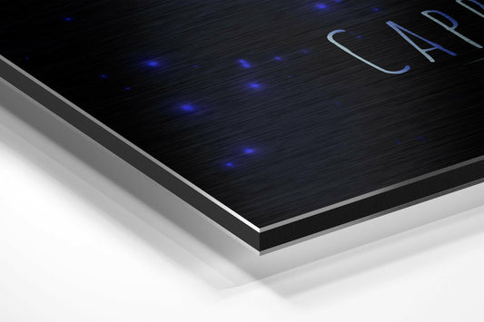 Capricorn zodiac sign in blue brushstrokes brushed aluminum panel corner close-up showing the brushed metal grain