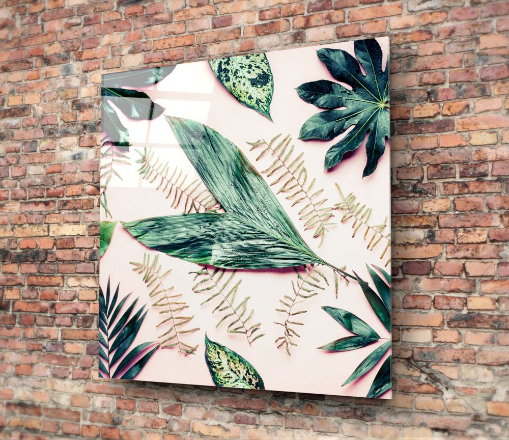 Tropical leaves on blush glass wall art hung on a red brick wall