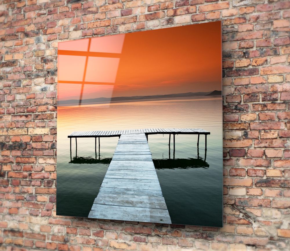 Orange sunset lake pier glass wall art on a red brick wall