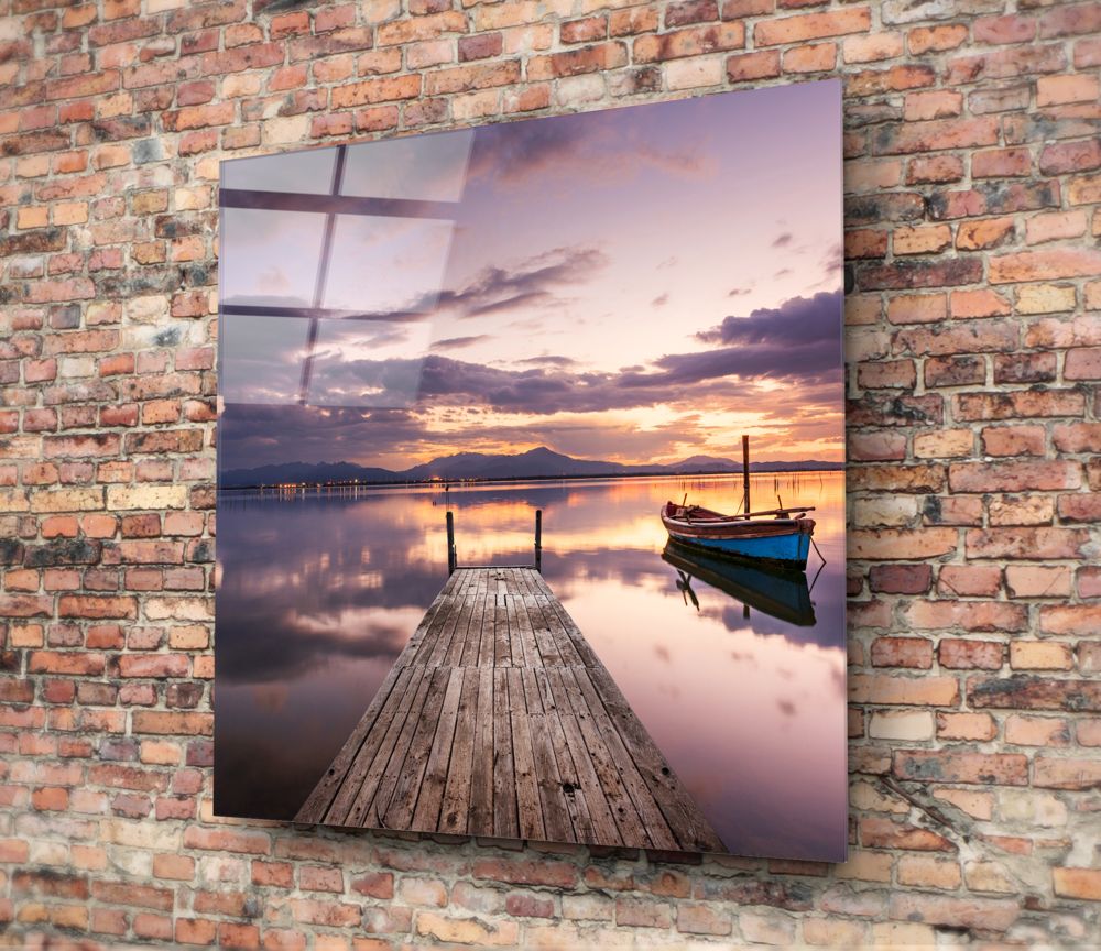 Purple dusk dock and boat glass wall art hung on a red brick wall