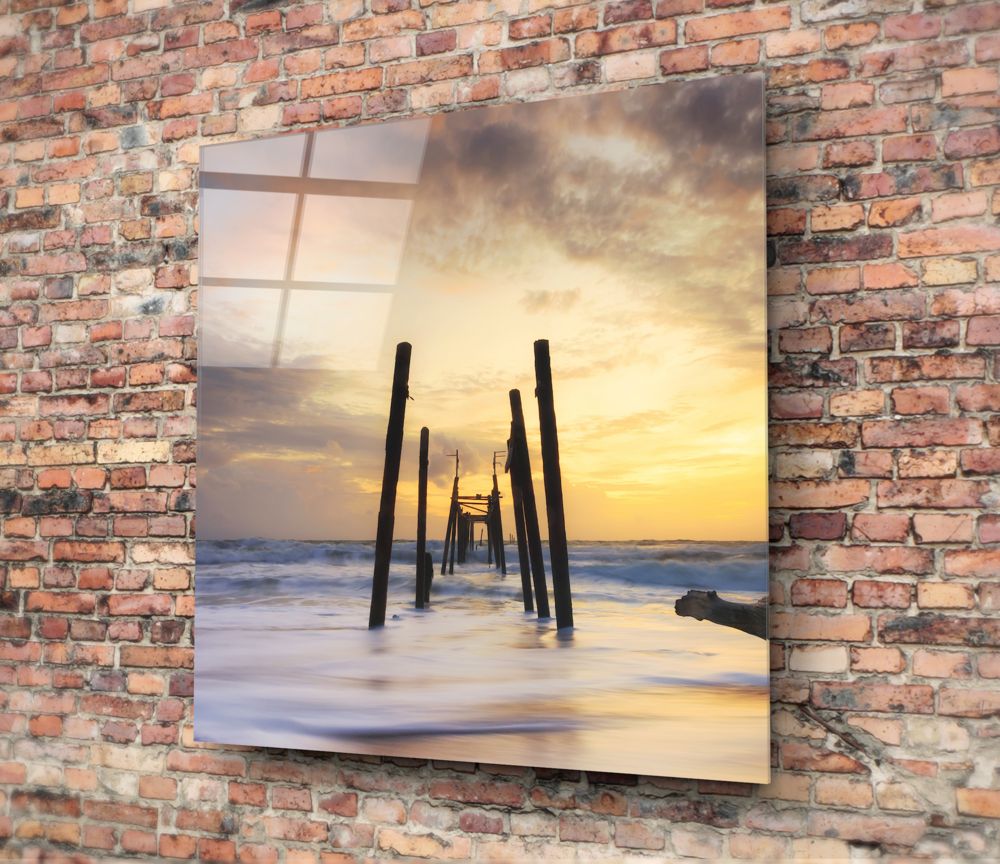 Golden sunset ruined pier glass wall art hung on a red brick wall