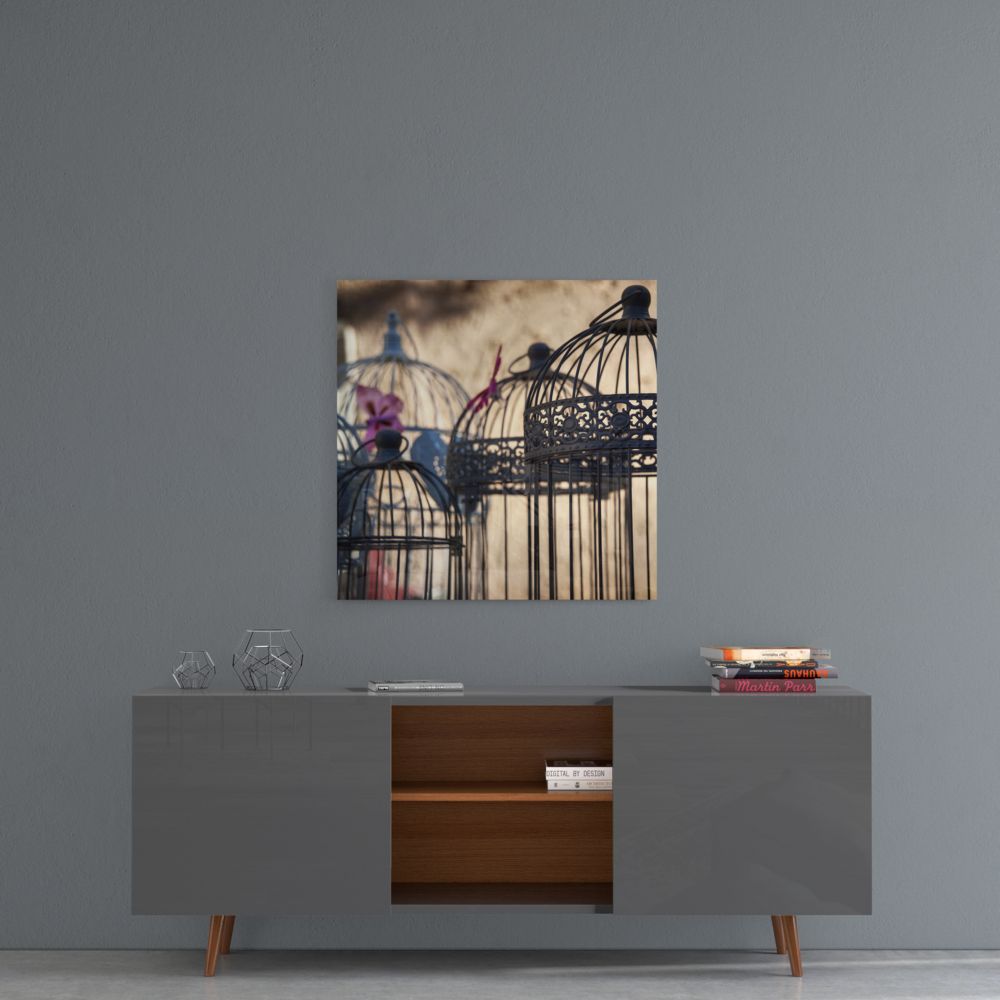 Ornate birdcages glass wall art above a gray sideboard with an open wood shelf on a gray wall