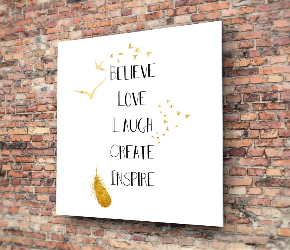 Inspirational words with a gold feather square glass wall art on a red brick wall