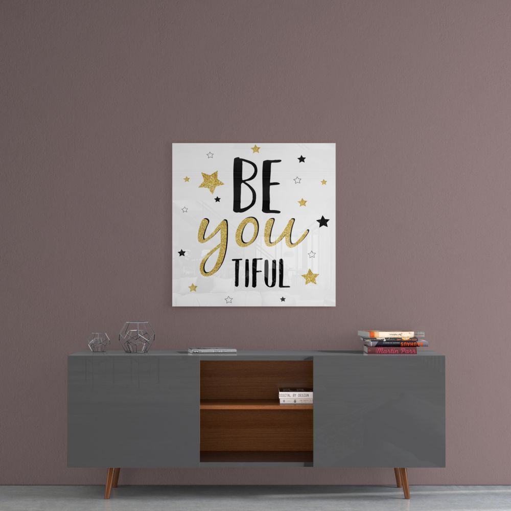 Be You Tiful gold stars typography glass wall art above a gray sideboard with a wood center cabinet