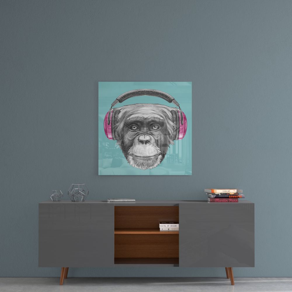 Chimpanzee with headphones glass wall art above a gray sideboard with an open wood shelf