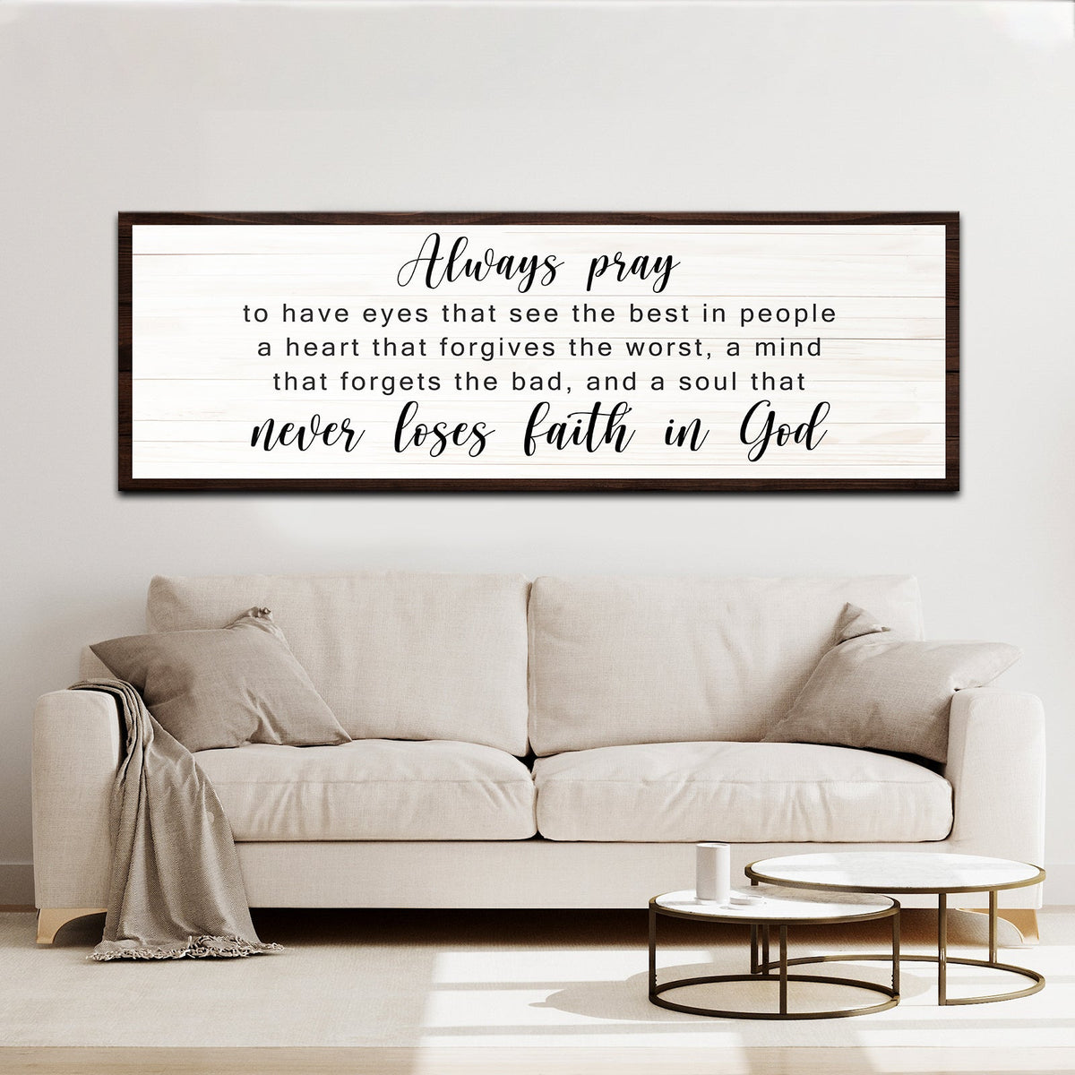 Second style of the Always pray canvas sign with a clean dark border on a white plank look, above a cream sofa