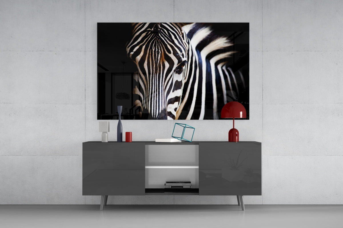 Zebra head on black glass wall art above a gray sideboard with a red table lamp