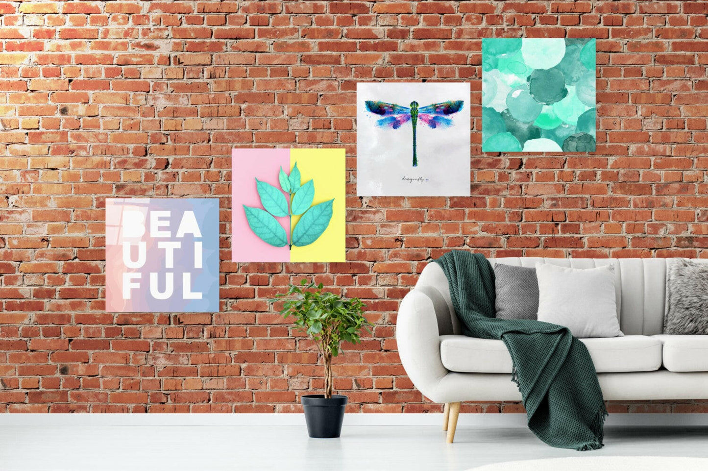 Pastel glass panels hung in a staggered line on a red brick wall above a white sofa and a potted tree