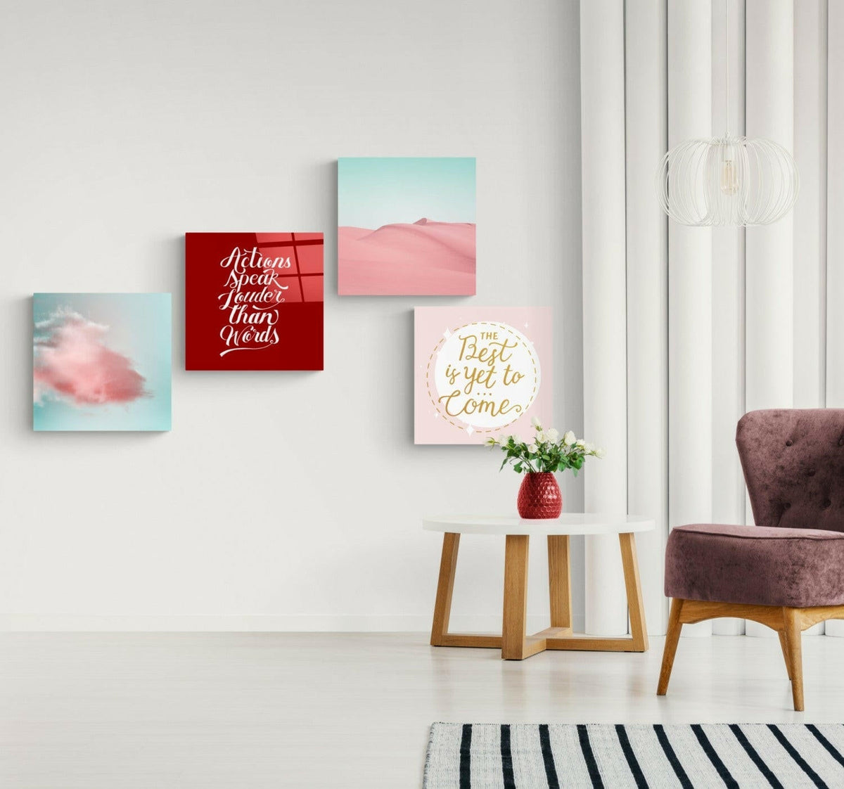Pink and mint four-panel glass set spaced on a white wall beside a mauve armchair and a round side table