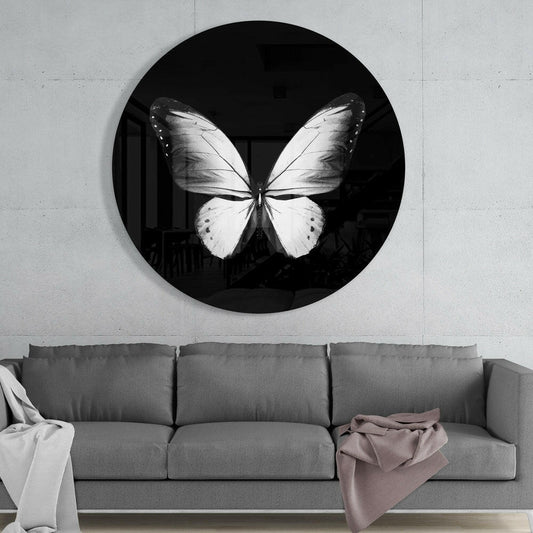 White butterfly round glass wall art above a gray sofa with white and pink throws