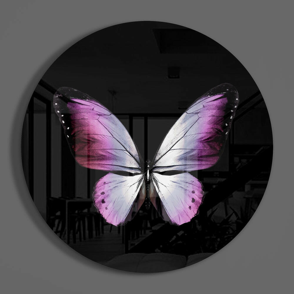 Pink butterfly round glass wall art hanging on a plain gray wall