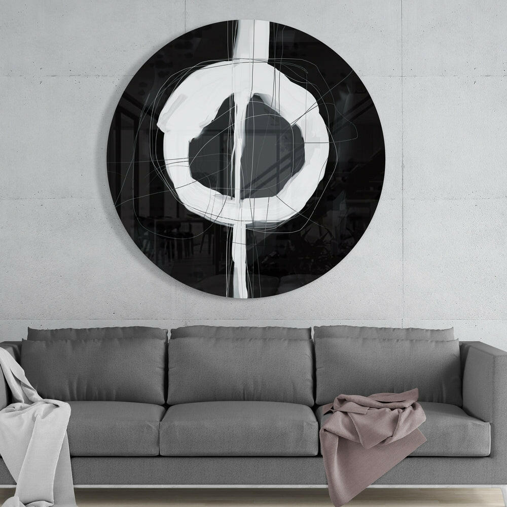 Black and white enso circle round glass wall art above a gray sofa with white and pink throws