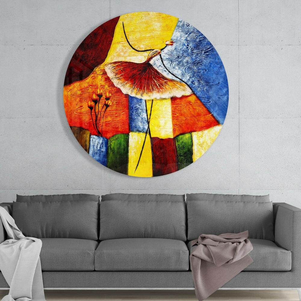 Abstract ballerina round glass wall art above a gray sofa with draped throws on a pale concrete wall