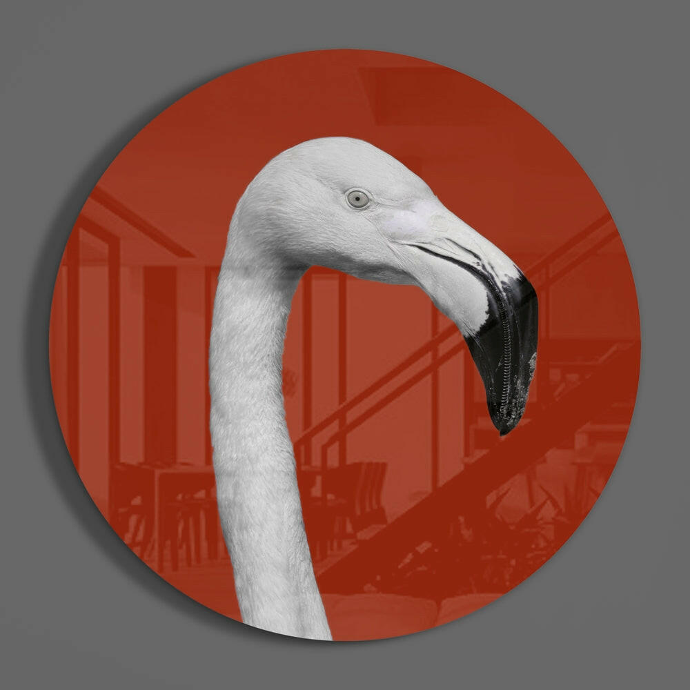 White flamingo on red round glass wall art hanging on a plain gray wall