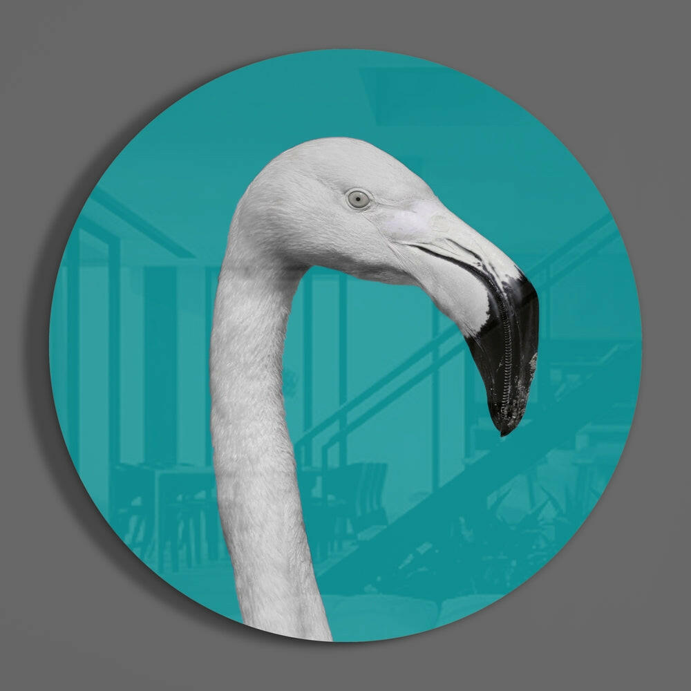 White flamingo on teal round glass wall art hanging on a plain gray wall