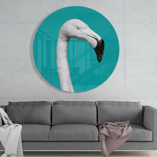White flamingo on teal round glass wall art above a gray sofa with white and pink throws