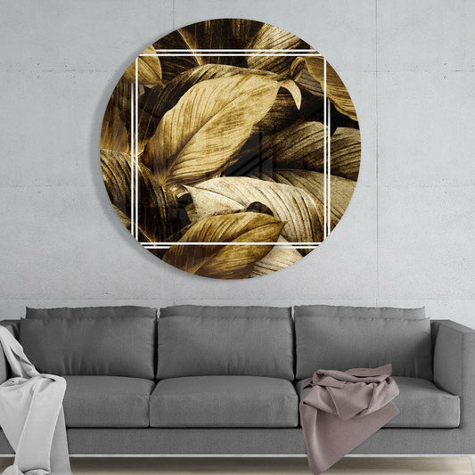 Golden sepia leaves round glass wall art above a gray sofa with a white throw and a mauve blanket on a pale concrete wall