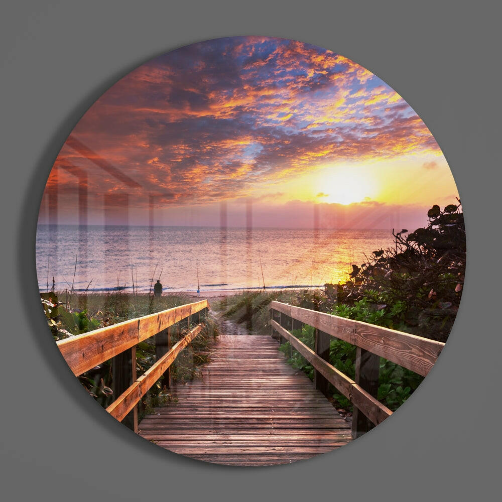 Beach boardwalk sunset round glass wall art on a plain gray wall, glossy glass disc seen from the front