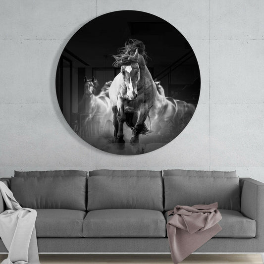 Black and white galloping horses round glass wall art above a gray sofa with a draped blanket