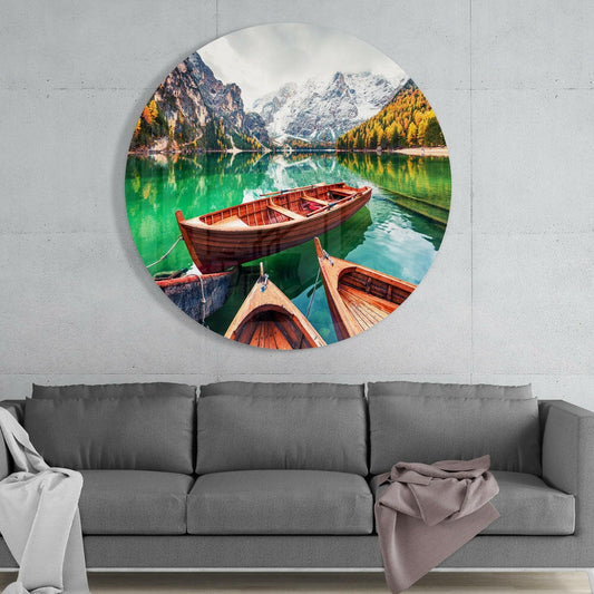 Alpine lake boats round glass wall art above a gray sofa with white and mauve throws