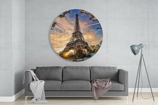 Eiffel Tower sunset round glass wall art above a gray sofa beside a tripod lamp