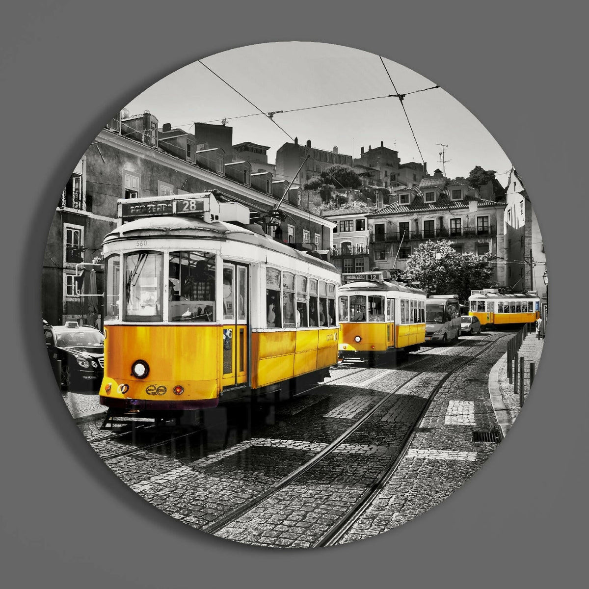 Yellow trams on cobblestones round glass wall art on a gray wall, showing the glossy glass face