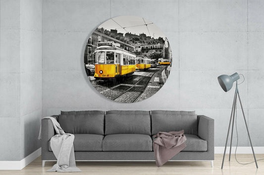 Yellow trams round glass wall art above a gray sofa beside a gray tripod floor lamp