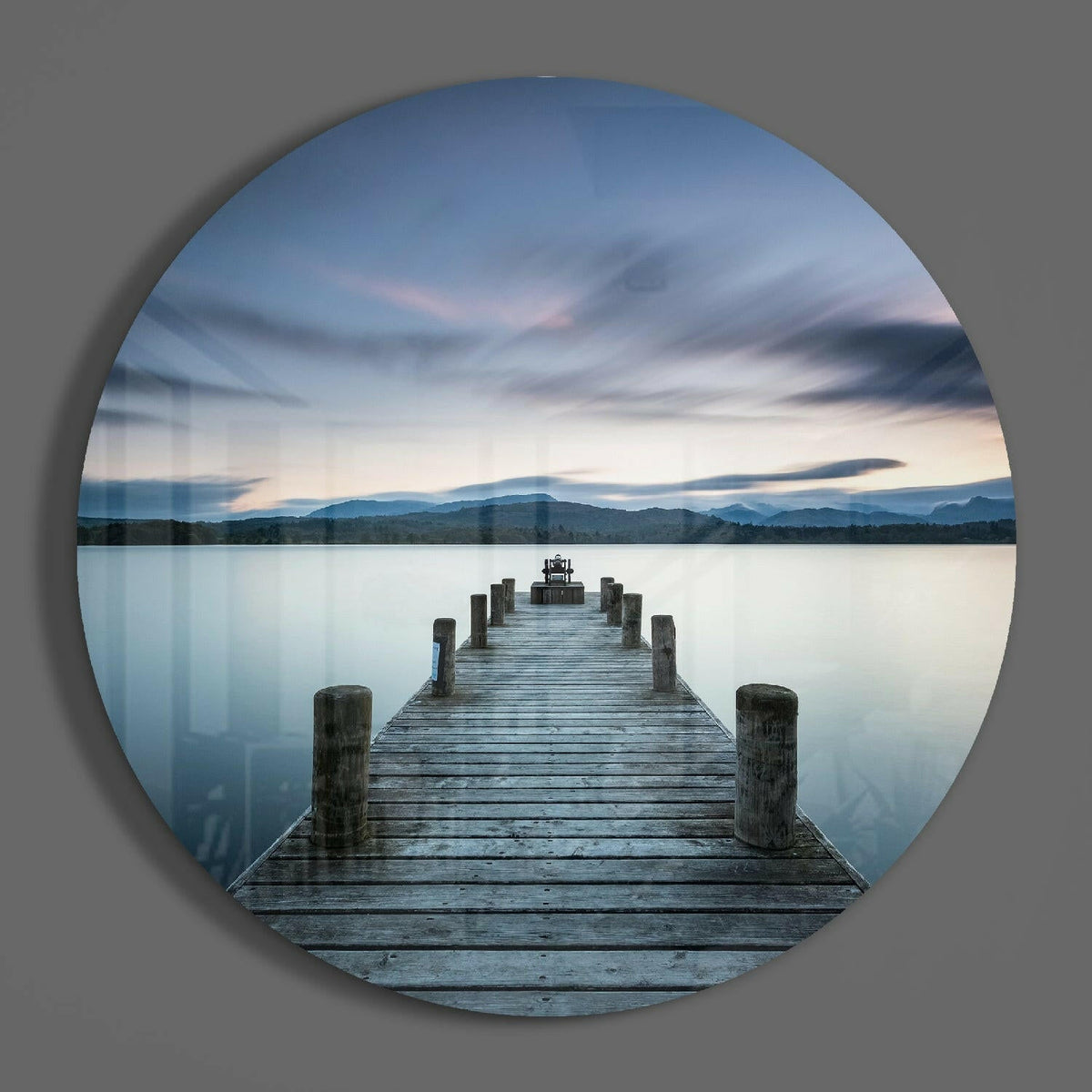Misty lake pier at dusk round glass wall art on a plain gray wall, glossy glass disc seen from the front