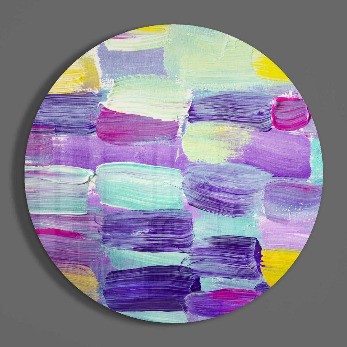 Purple and teal brushstroke circle of glass on a plain gray wall