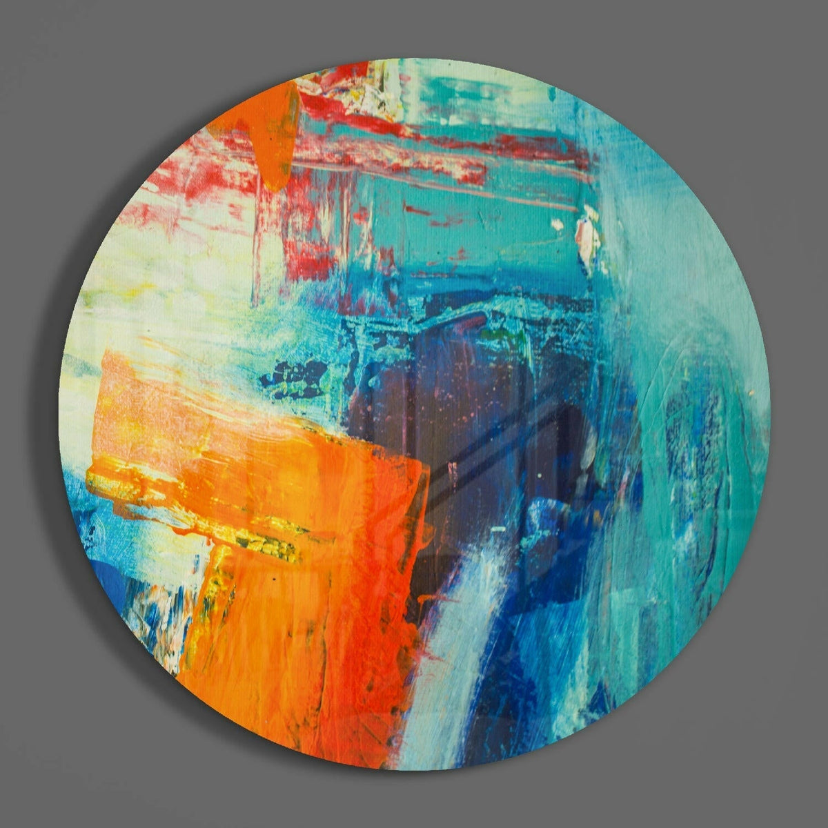Orange and teal abstract round glass wall art hanging on a plain gray wall