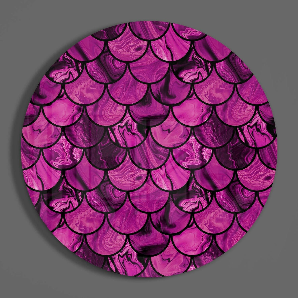 Magenta fish scale pattern round glass wall art on a plain gray wall, glossy glass disc seen from the front