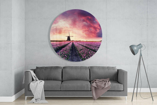Tulip field round glass wall art above a gray sofa with a pink throw and a floor lamp