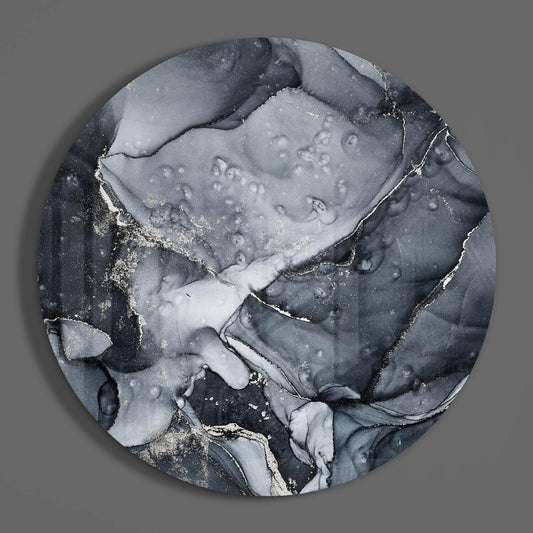 Charcoal silver ink marble round glass wall art on a plain gray wall, glossy glass disc seen from the front