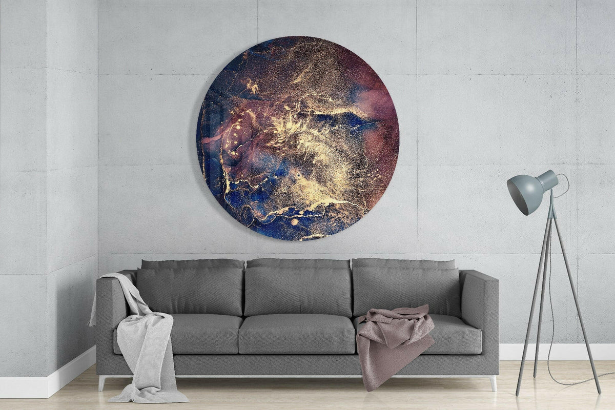 Navy blue gold cosmic ink round glass wall art above a gray sofa beside a tripod floor lamp on a pale concrete wall