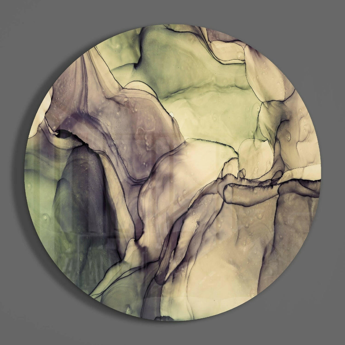 Sage green marble ink round glass disc casting a soft shadow on a gray wall