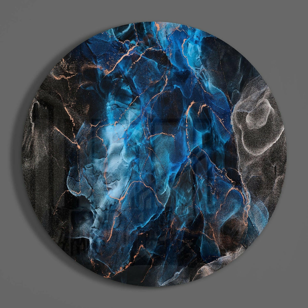 Blue marble round glass wall art hanging on a plain gray wall