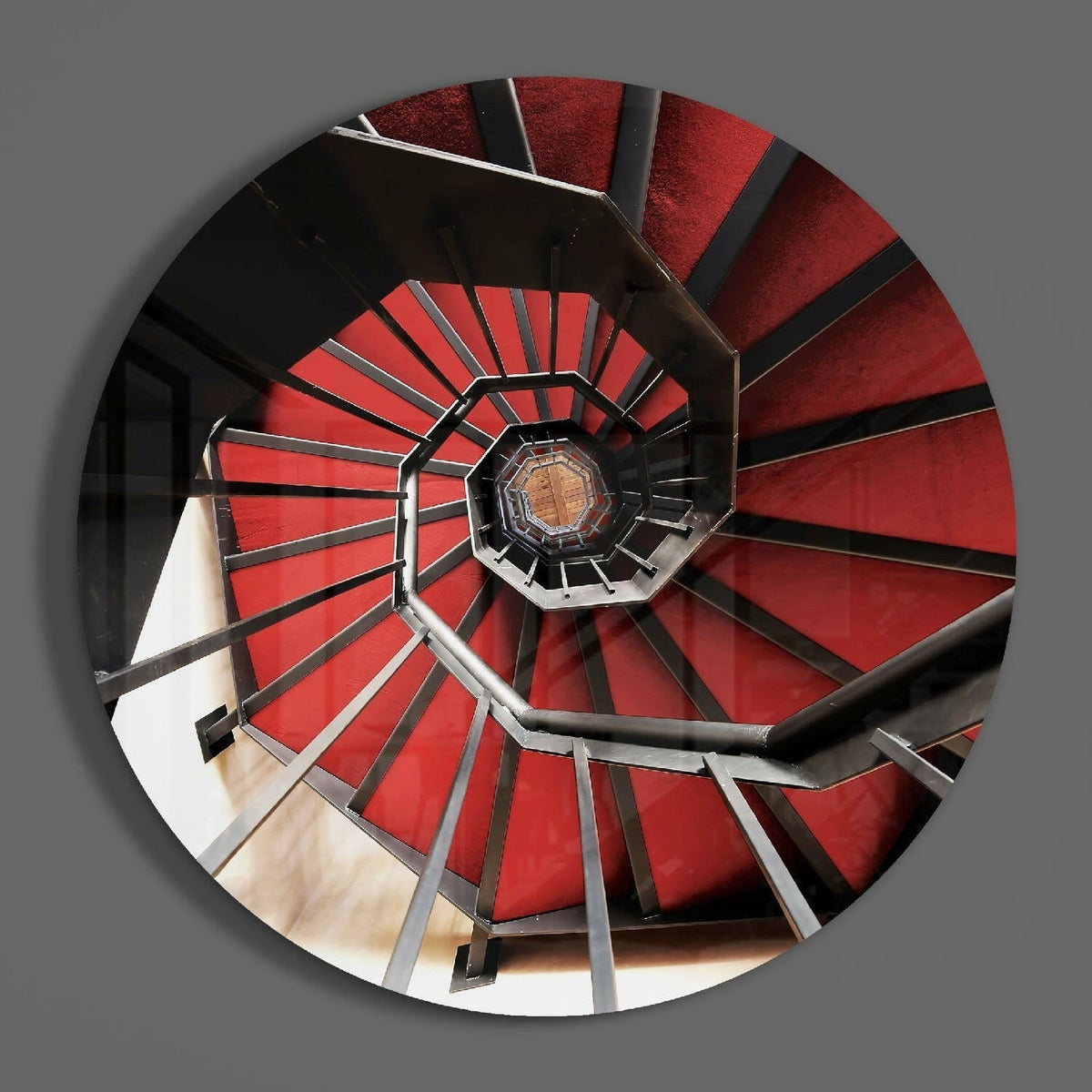 Red stairwell spiral round glass piece shown on a plain gray wall