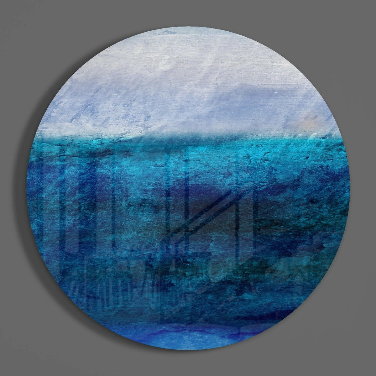 Blue abstract horizon round glass wall art on a plain gray wall, glossy glass disc seen from the front