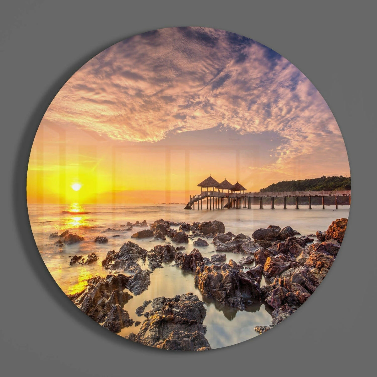 Golden sunrise beach pier round glass piece shown on a plain gray wall