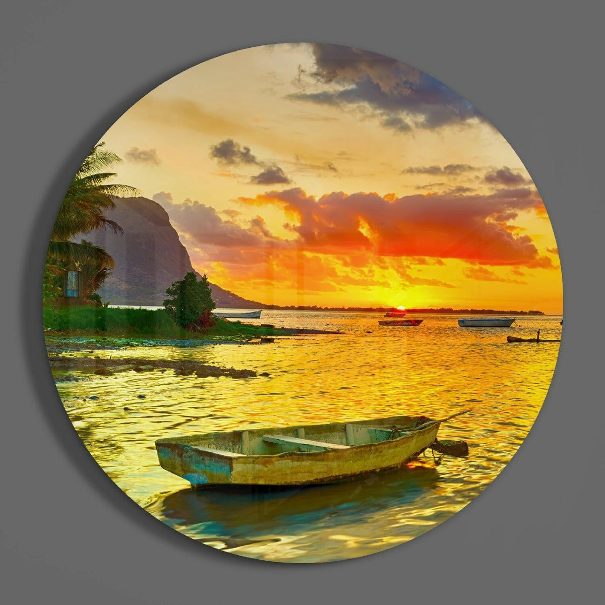 Boat on a golden sunset lagoon round glass wall art on a plain gray wall, glossy glass disc seen from the front