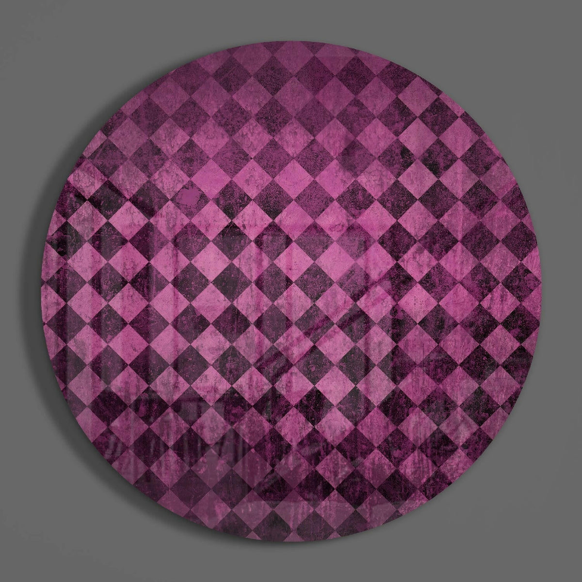 Pink diamond checker round glass wall art hanging on a plain gray wall