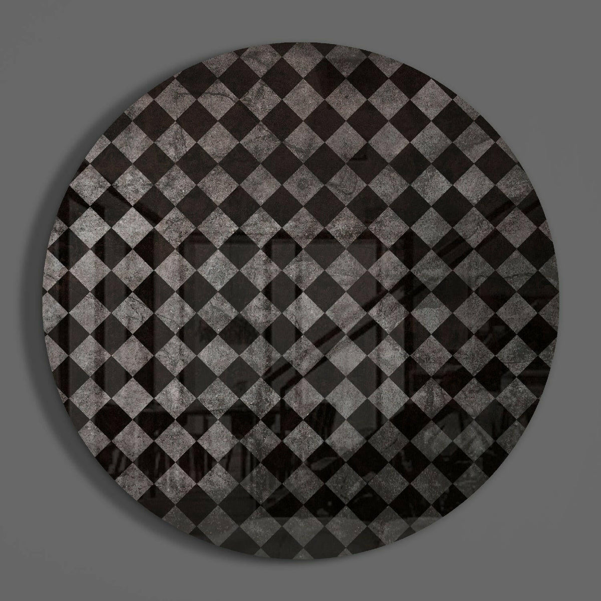 Charcoal diamond checker round glass wall art on a plain gray wall, glossy glass disc seen from the front