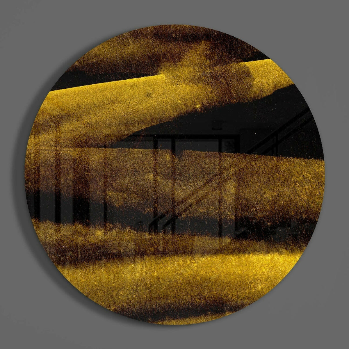 Gold dust ridges round glass disc casting a soft shadow on a gray wall