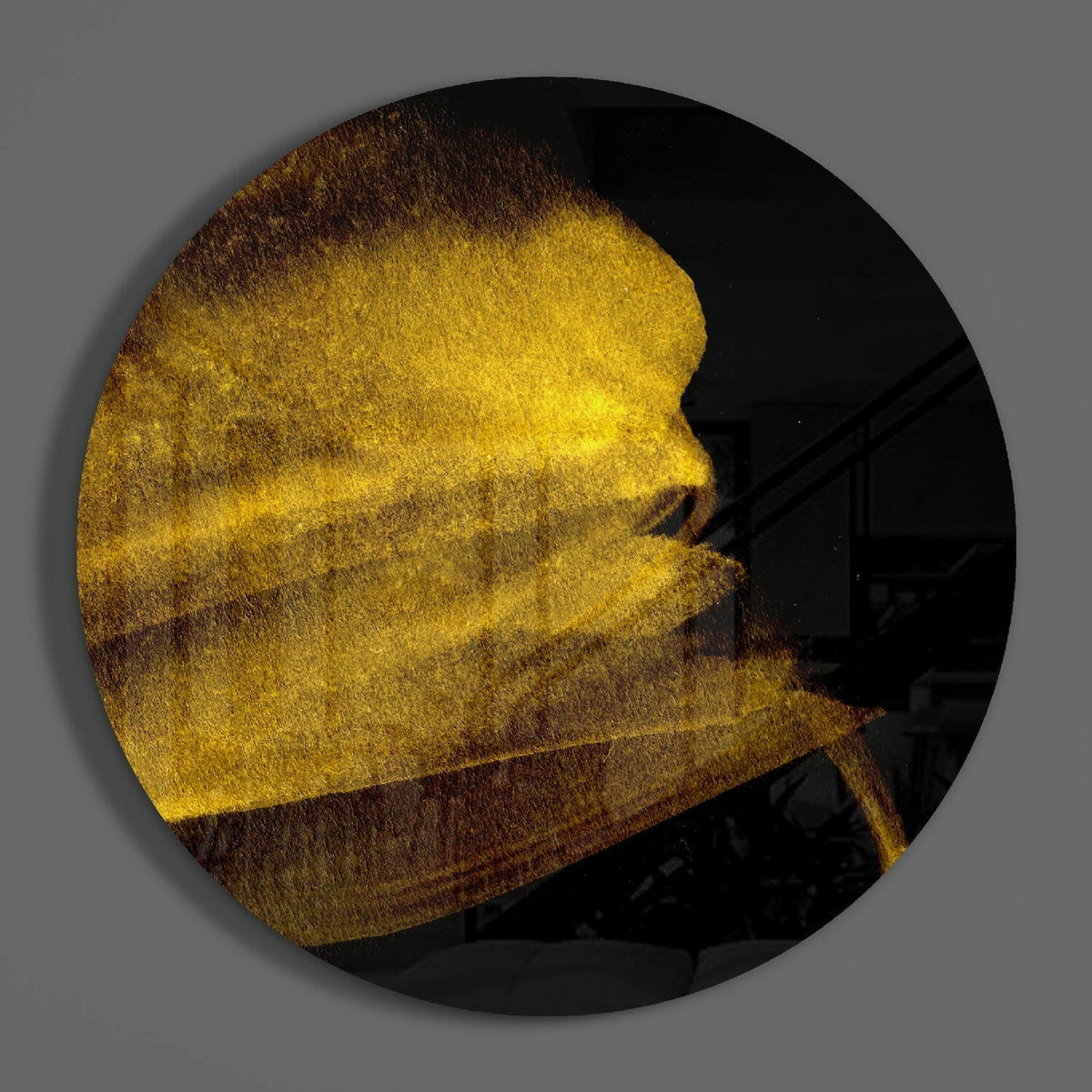 Golden shimmer sweep round glass disc casting a soft shadow on a gray wall