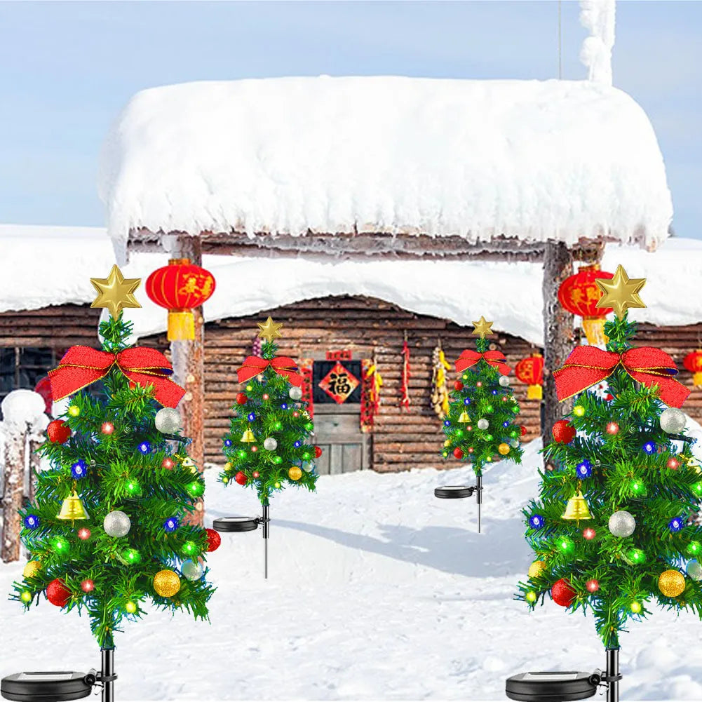 Solar powered Christmas trees in front of a snow-covered cabin with festive decorations.