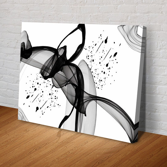 Black ink swirls on white canvas leaning at an angle on a wood floor against a brick wall