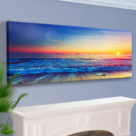 Pink and gold sky over blue surf canvas above a white mantel, angled view