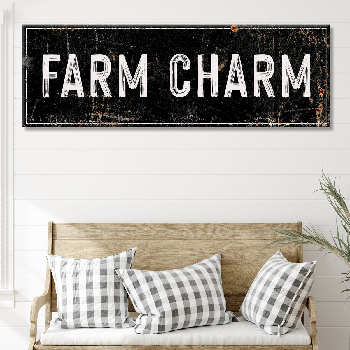 Farm Charm canvas sign in the black distressed style above a wooden bench with plaid pillows