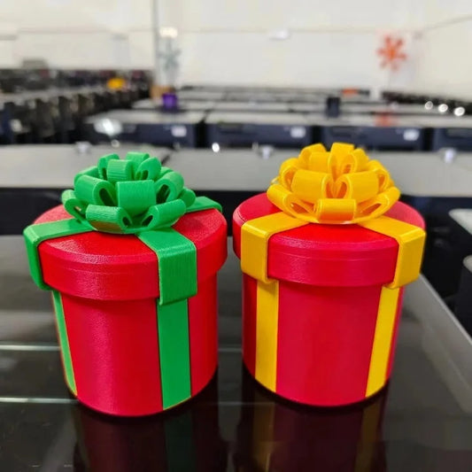 Two colorful 3D printed Christmas gift boxes with bows - red gift box with green and yellow ribbons