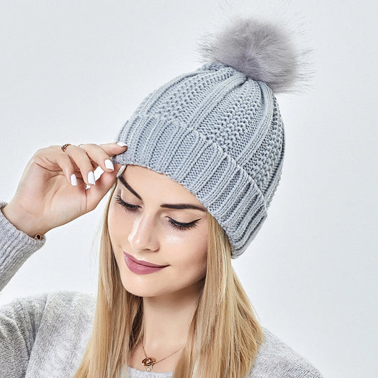 Woman wearing satin lined winter beanie hat showing cable knit pattern and pompom
